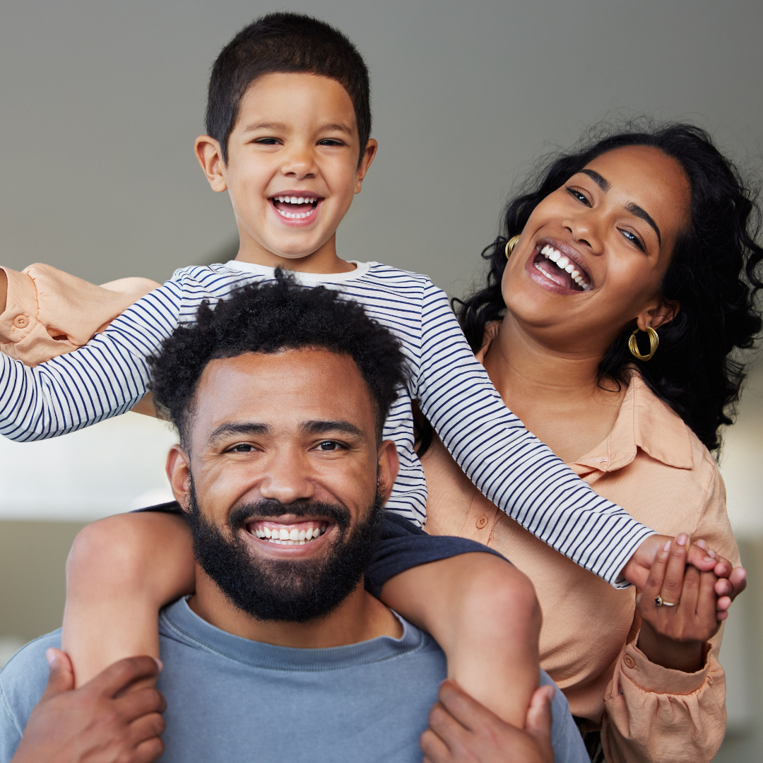 Happy family smiling together with daughter on father's shoulders